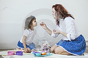 Young beautiful woman mother and daughter with toy dishes, sweet