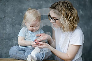 Young beautiful woman mother holding show small white balls on palm for little cherubic girl baby daughter. Motherhood.