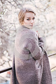 Young beautiful woman near trees in blossom in spring. Hair style bound