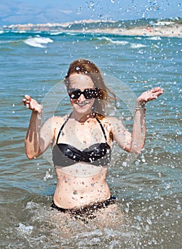Young beautiful woman in ocean making water splashes