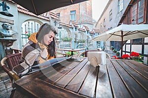 Young beautiful woman order food in outdoor cafe in chill morning