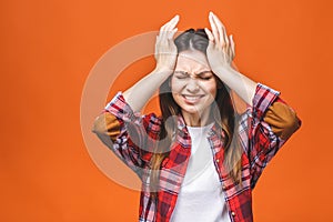 Young beautiful woman over isolated orange background suffering from headache desperate and stressed because pain and migraine.