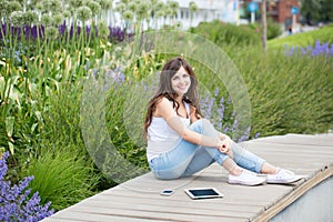 Young beautiful woman in the park with gadgets