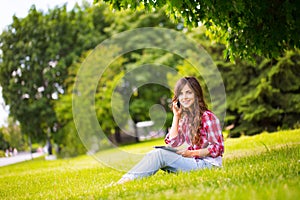 Young beautiful woman in the park with gadgets