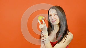 Young Beautiful Woman with Perfect Skin Eating Red Apple on Orange Background. Dieting Concept. Healthy Food.