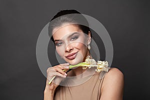 Young beautiful woman with perfect skin wearing pearls earring smiling at the camera on black background