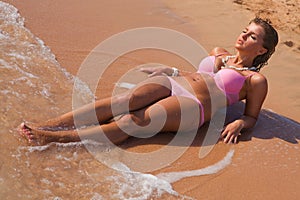 Young beautiful woman in pink bikini laying