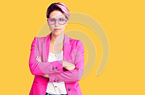 Young beautiful woman with pink hair wearing business jacket and glasses skeptic and nervous, disapproving expression on face with