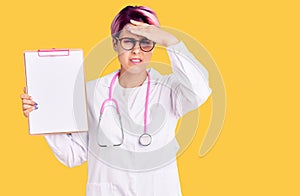 Young beautiful woman with pink hair wearing doctor stethoscope holding clipboard with medical report stressed and frustrated with