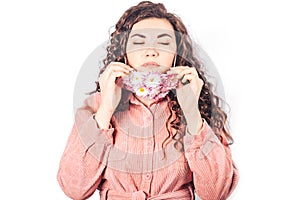 Young beautiful woman in pink suit on white background. She wears protective mask of blooming flowers on her face. Breathe fresh