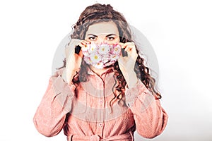 Young beautiful woman in pink suit on white background. She wears protective mask of blooming flowers on her face. Breathe fresh