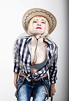 Young beautiful woman in a plaid shirt jeans and a cowboy hat