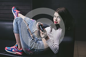 Young beautiful woman playing a console game on the couch fashi