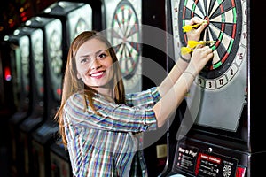 Young beautiful woman playing darts in a club