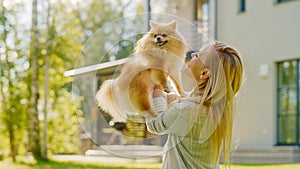 Young Beautiful Woman Plays with Her Cute Little Pomeranian Dog, Holds Her, Caresses, Cuddles, and