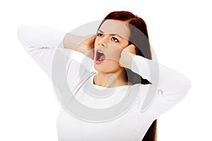 Young beautiful woman plugging her ears and screaming