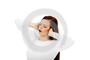 Young beautiful woman plugging her ears and screaming