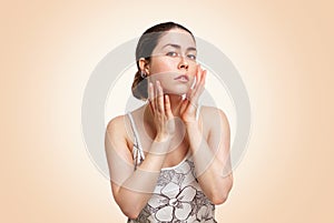 A young beautiful woman poses on a beige background, showing a healthy and well-groomed face. Copy space. The concept of