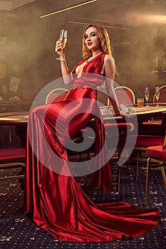 Young beautiful woman is posing against a poker table in luxury casino.