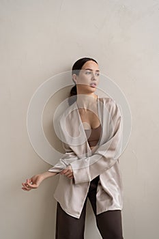 young beautiful woman posing in beige lingerie in the studio, standing near the window