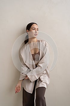 young beautiful woman posing in beige lingerie in the studio, standing near the window