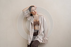 young beautiful woman posing in beige lingerie in the studio, standing near the window