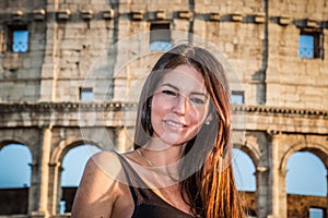 Young beautiful woman posing in front of the Colosseum. Marble arches ruins over a blue sky, Rome, Italy