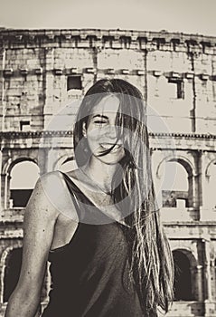 Young beautiful woman posing in front of the Colosseum. Marble arches ruins over a blue sky, Rome, Italy