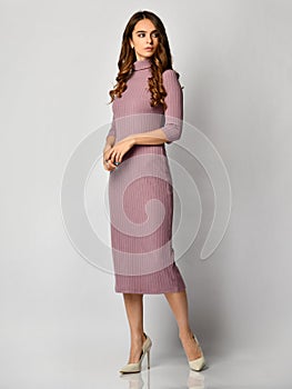Young beautiful woman posing in new light purple fashion winter dress on high hills full body