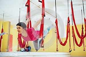 Young beautiful woman practicing yoga Fly with a hammock in the bright studio. The concept of mental and physical health