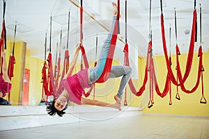 Young beautiful woman practicing yoga Fly with a hammock in the bright studio. The concept of mental and physical health