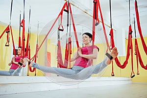 Young beautiful woman practicing yoga Fly with a hammock in the bright studio. The concept of mental and physical health