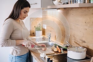 A young beautiful woman is preparing lunch in her kitchen at home. Vegan