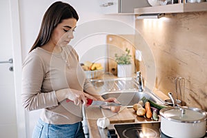 A young beautiful woman is preparing lunch in her kitchen at home. Vegan