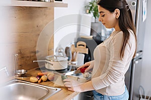 A young beautiful woman is preparing lunch in her kitchen at home. Vegan