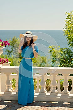 Young beautiful woman on the promenade in azure long dress takes