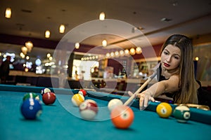 Young and beautiful woman in pub playing billiard