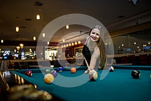 Young and beautiful woman in pub playing billiard