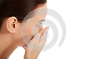 Young beautiful woman putting contact lens.