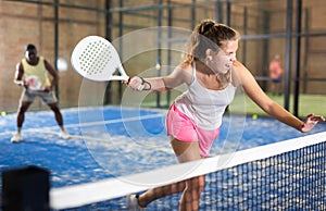 Young beautiful woman with racket playing padel