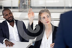 Young beautiful woman raise hand for question at presentation.