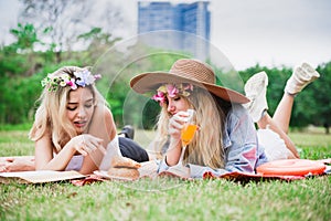 Young beautiful woman read text book and lay on mat and grass field with friend