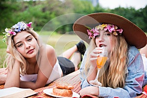 Young beautiful woman read text book and lay on mat and grass field with friend