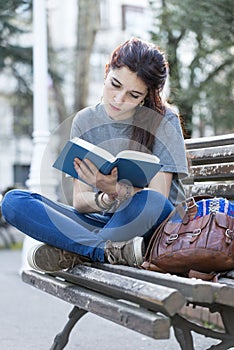 Young beautiful woman reading blue book in the street.