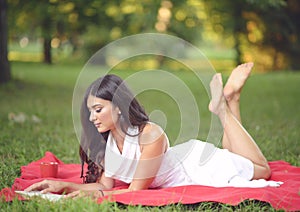 Young beautiful woman reading book outdoors in park on a sunny day