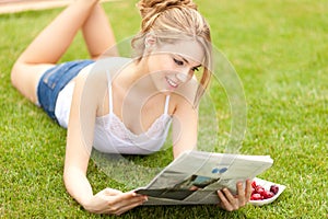 Young beautiful woman reading newspaper