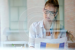 Young beautiful woman reading newspaper at home.