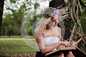 Young beautiful woman reading in the park