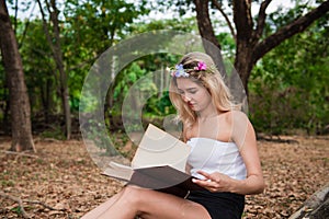 Young beautiful woman reading in the park