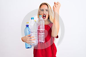 Young beautiful woman recycling plastic bottles standing over isolated white background annoyed and frustrated shouting with